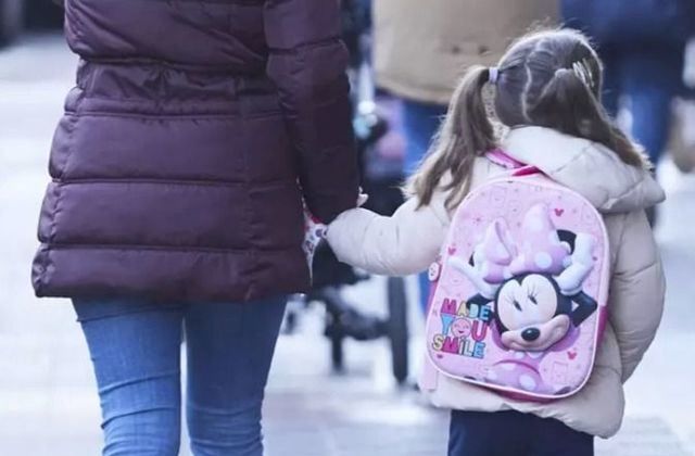 Una niña, acompañada de un madre, durante la vuelta al colegio