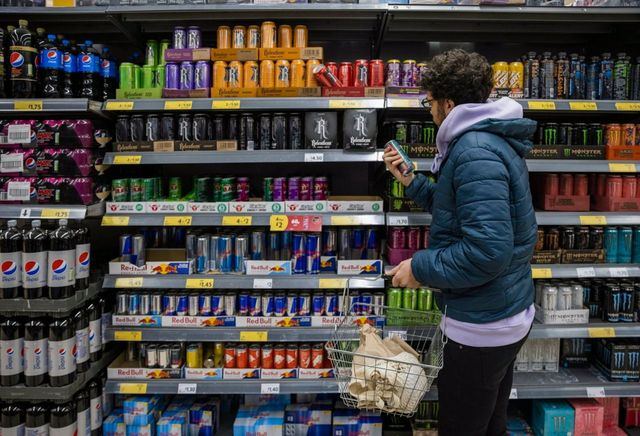 Un joven mira la sección de bebidas energéticas en el supermercado. - SOLSTOCK - Archivo