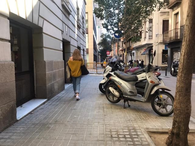 Motos aparcadas en la acera en una calle del barrio de la Vila de Gràcia.